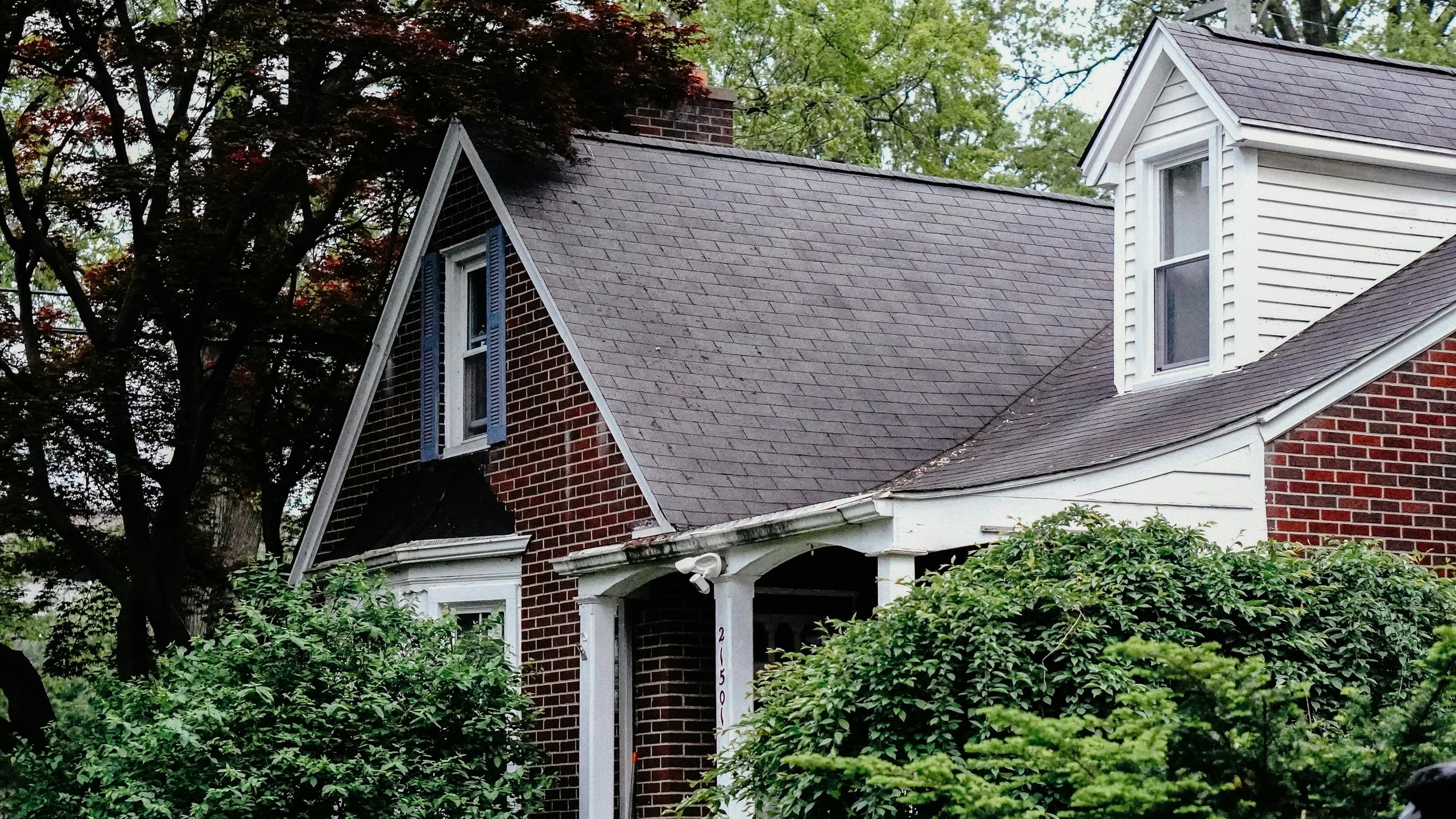 A cozy brick home behind green trees